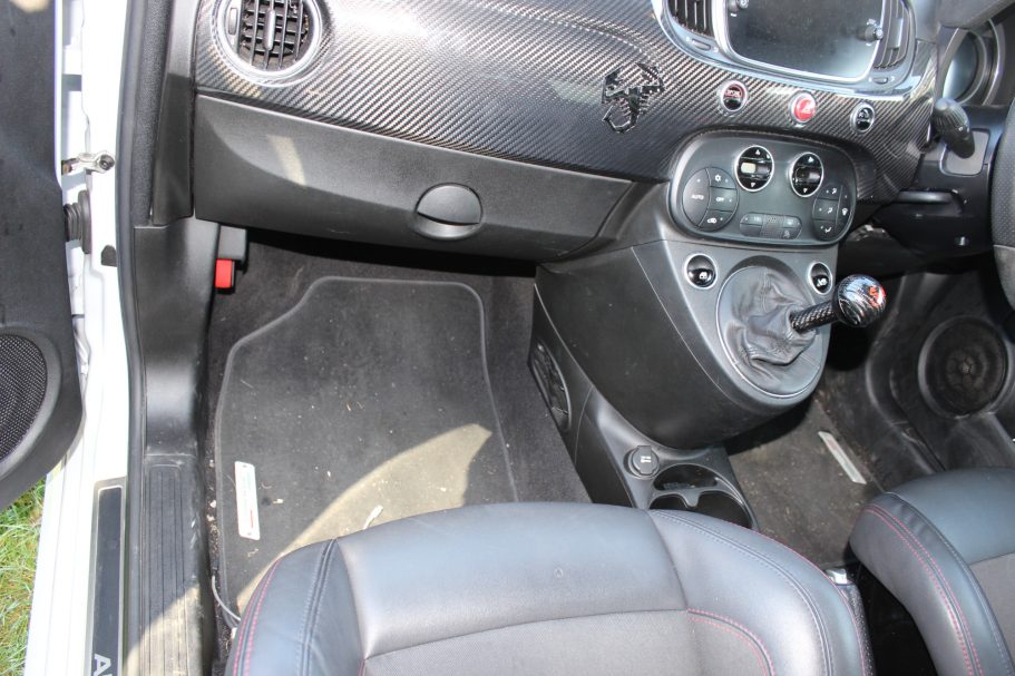 Interior of a car showing dashboard controls and floor mat.