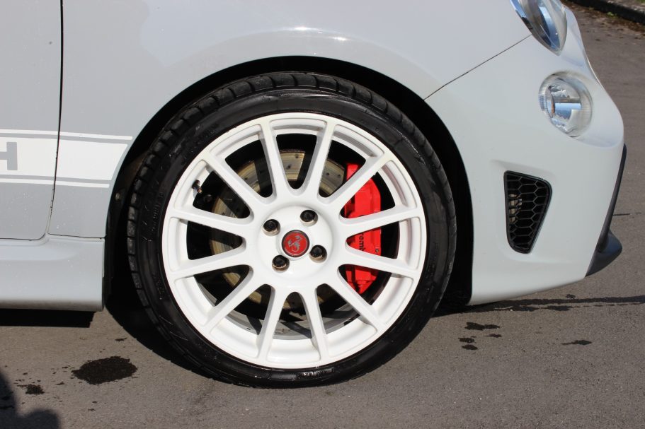 White alloy wheel with a red brake caliper on a silver car.