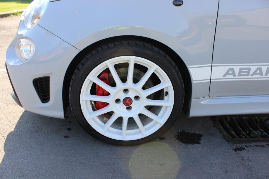 Close-up of a silver car wheel with white alloy rim and red brake caliper.