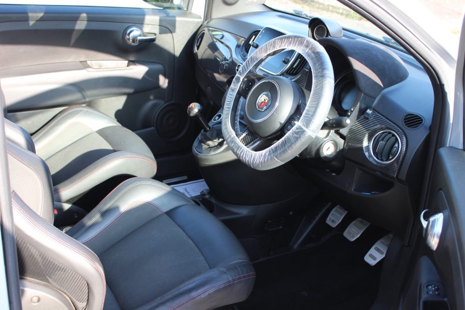 Car interior showing front seats, steering wheel, and dashboard controls.