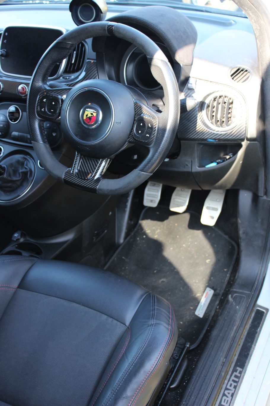 Interior of a car showing the steering wheel, dashboard, and pedals.